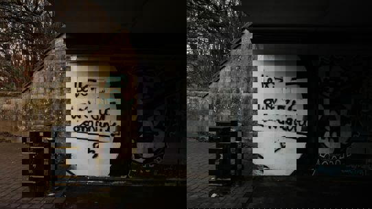 Underneath an overpass with graffiti on the wall saying "Lets love our community"