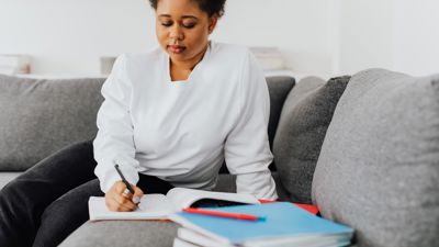 A woman writing in a notepad on a sofa